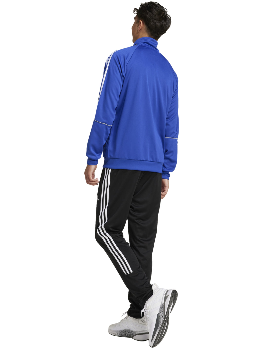 Hombre vistiendo conjunto deportivo Adidas con chaqueta azul y pantalón negro con franjas blancas laterales.