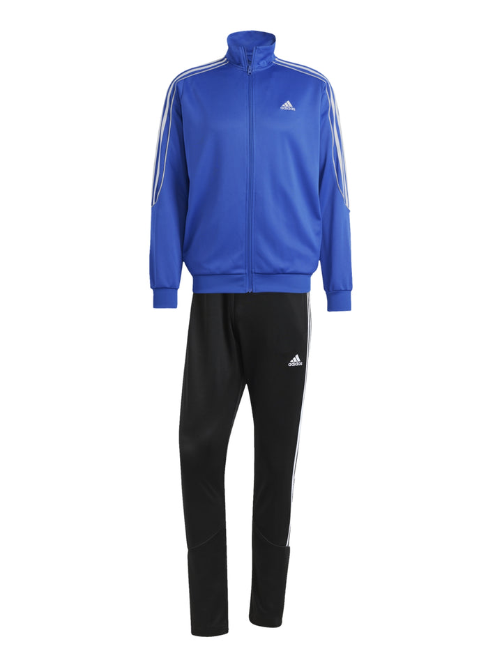 Hombre vistiendo conjunto deportivo Adidas con chaqueta azul y pantalón negro con franjas blancas laterales.