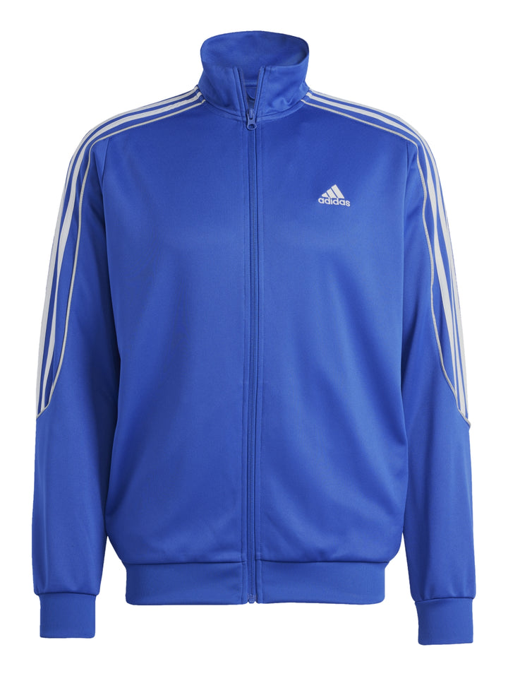 Hombre vistiendo conjunto deportivo Adidas con chaqueta azul y pantalón negro con franjas blancas laterales.