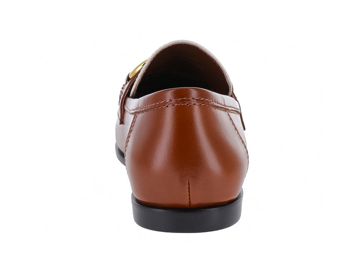 Zapato tipo mocasín bicolor en tonos café tan y hueso con herraje dorado frontal.