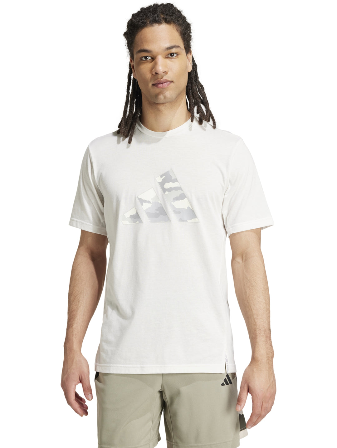 Hombre vistiendo playera blanca Adidas con logo gráfico de camuflaje en el pecho.
