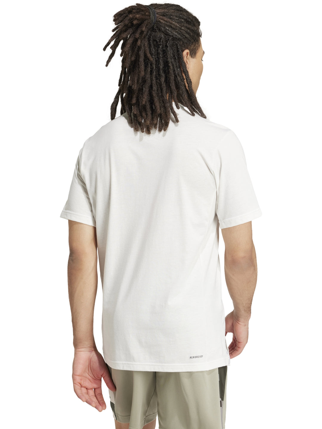Hombre vistiendo playera blanca Adidas con logo gráfico de camuflaje en el pecho.