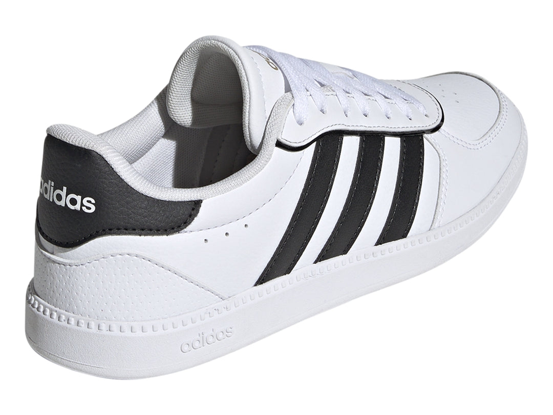 Tenis Adidas blancos con tres franjas negras laterales y suela blanca.