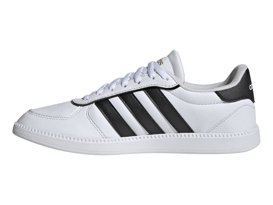 Tenis Adidas blancos con tres franjas negras laterales y suela blanca.
