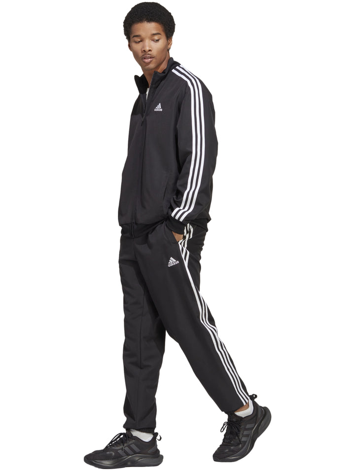 Conjunto deportivo Adidas negro con tres franjas blancas laterales compuesto por chaqueta y pantalón.