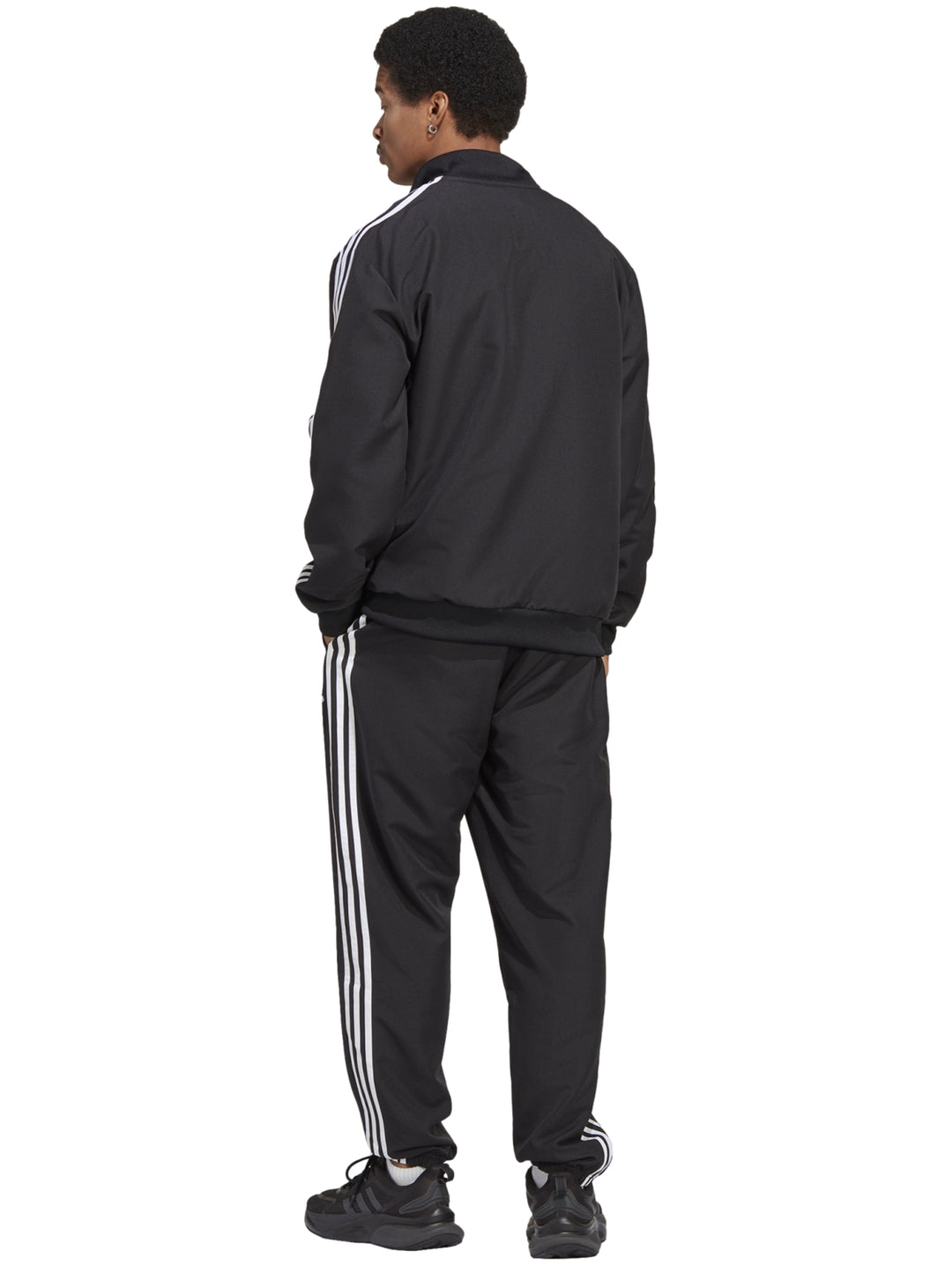 Conjunto deportivo Adidas negro con tres franjas blancas laterales compuesto por chaqueta y pantalón.
