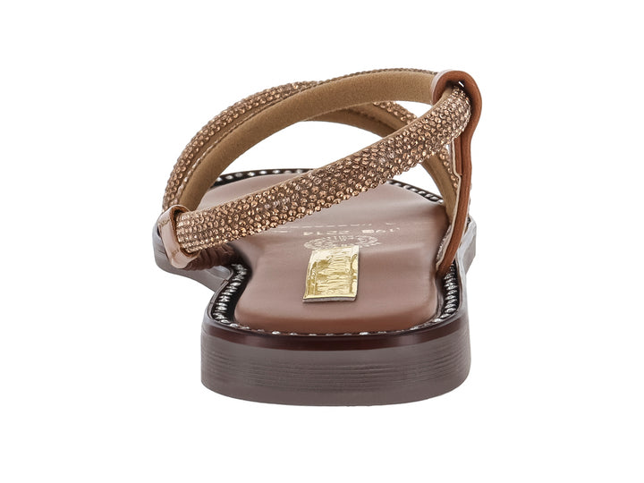 Sandalia plana color tan con tiras brillantes y suela marrón.
