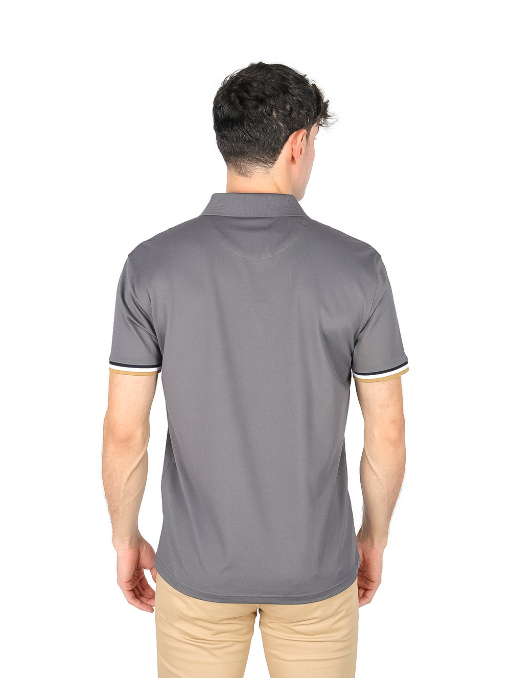 Hombre vistiendo playera polo color charcoal con detalles en blanco y dorado en el cuello y mangas.