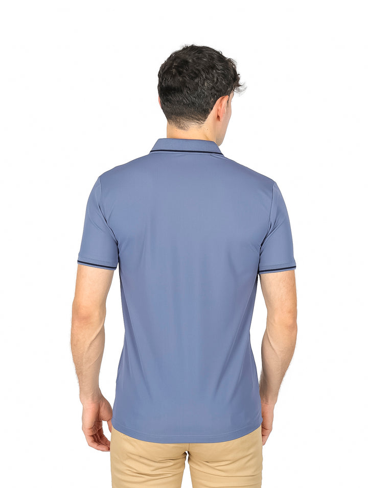 Hombre vistiendo playera tipo polo color azul gris con detalles oscuros en cuello y mangas.