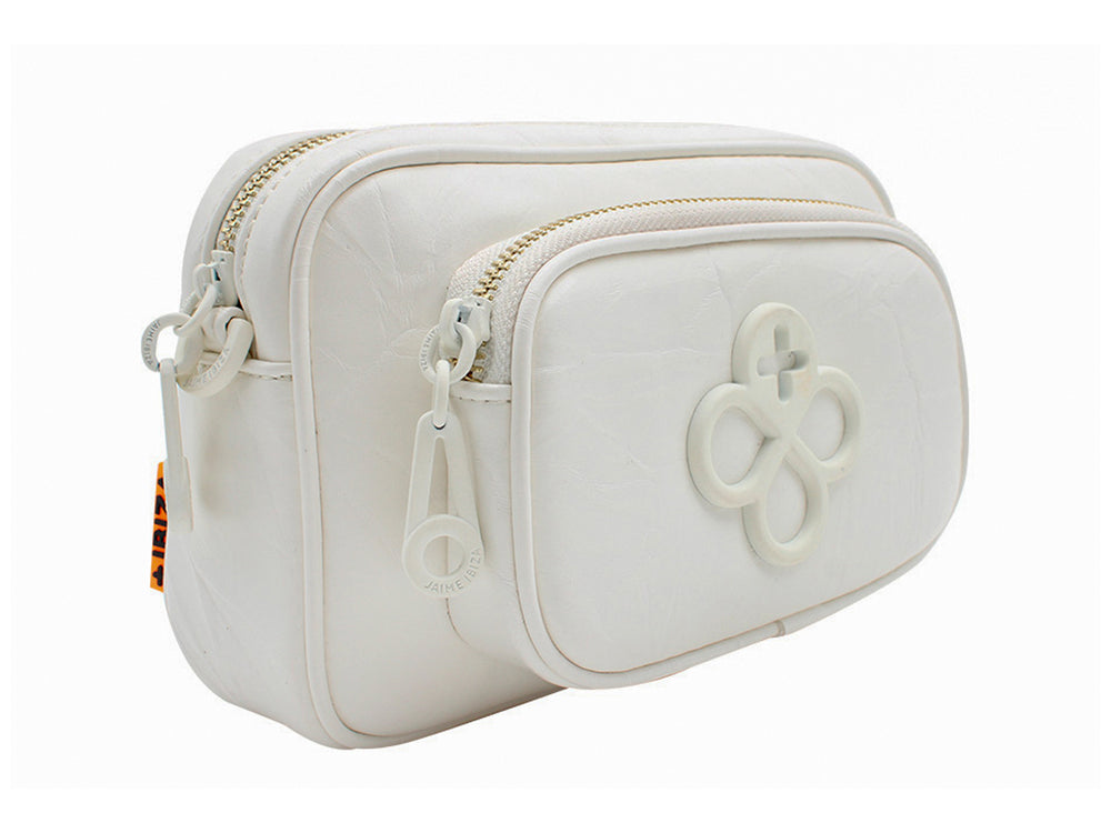 Bolso pequeño blanco de Jaime Ibiza con detalle decorativo frontal y llavero circular en color naranja.