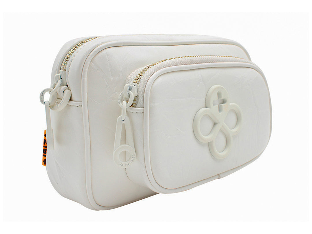Bolso pequeño blanco de Jaime Ibiza con detalle decorativo frontal y llavero circular en color naranja.