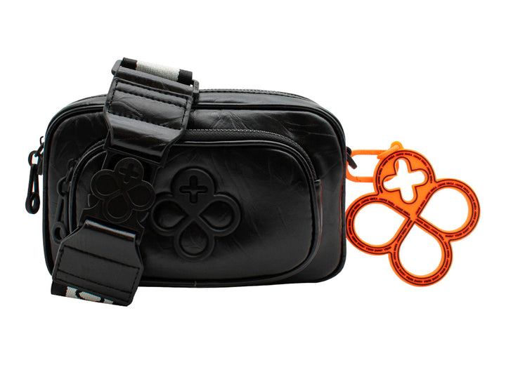 Bolso pequeño de color negro con correa y un accesorio colgante circular en color naranja.