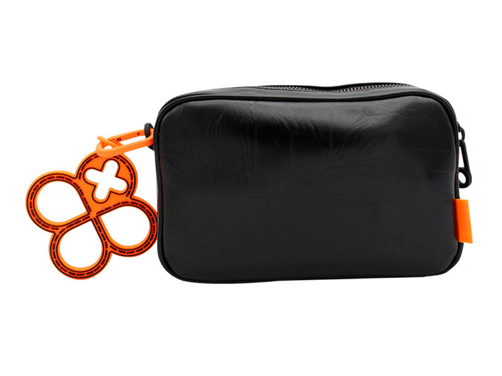 Bolso pequeño de color negro con correa y un accesorio colgante circular en color naranja.
