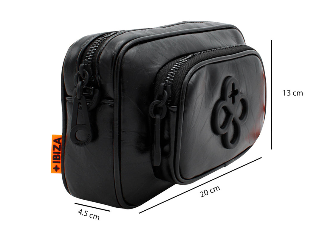 Bolso pequeño de color negro con correa y un accesorio colgante circular en color naranja.