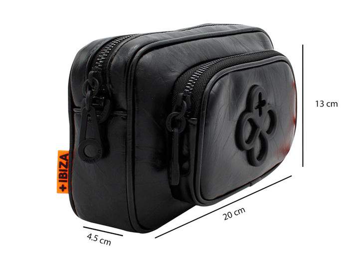 Bolso pequeño de color negro con correa y un accesorio colgante circular en color naranja.