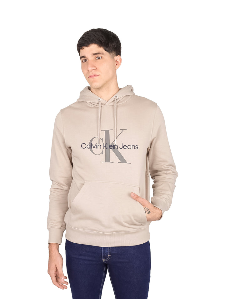 Hombre vistiendo sudadera con capucha color beige de Calvin Klein Jeans con logotipo en el pecho.