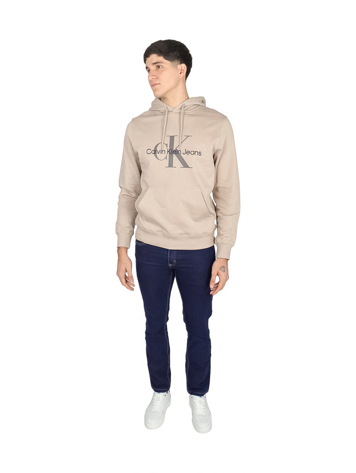 Hombre vistiendo sudadera con capucha color beige de Calvin Klein Jeans con logotipo en el pecho.