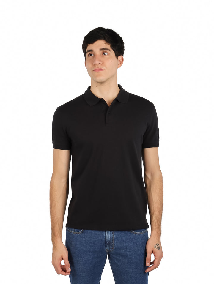 Hombre vistiendo una camiseta polo negra de manga corta Calvin Klein.