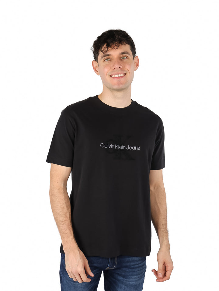 Hombre vistiendo una playera negra de manga corta con estampado de Calvin Klein Jeans en el pecho.