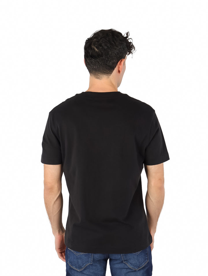 Hombre vistiendo una playera negra de manga corta con estampado de Calvin Klein Jeans en el pecho.