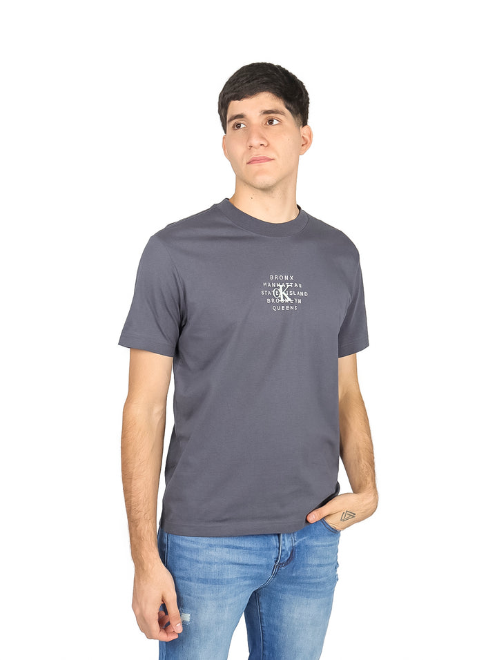 Hombre vistiendo una camiseta de manga corta color gris oscuro con estampado de texto blanco en el pecho.