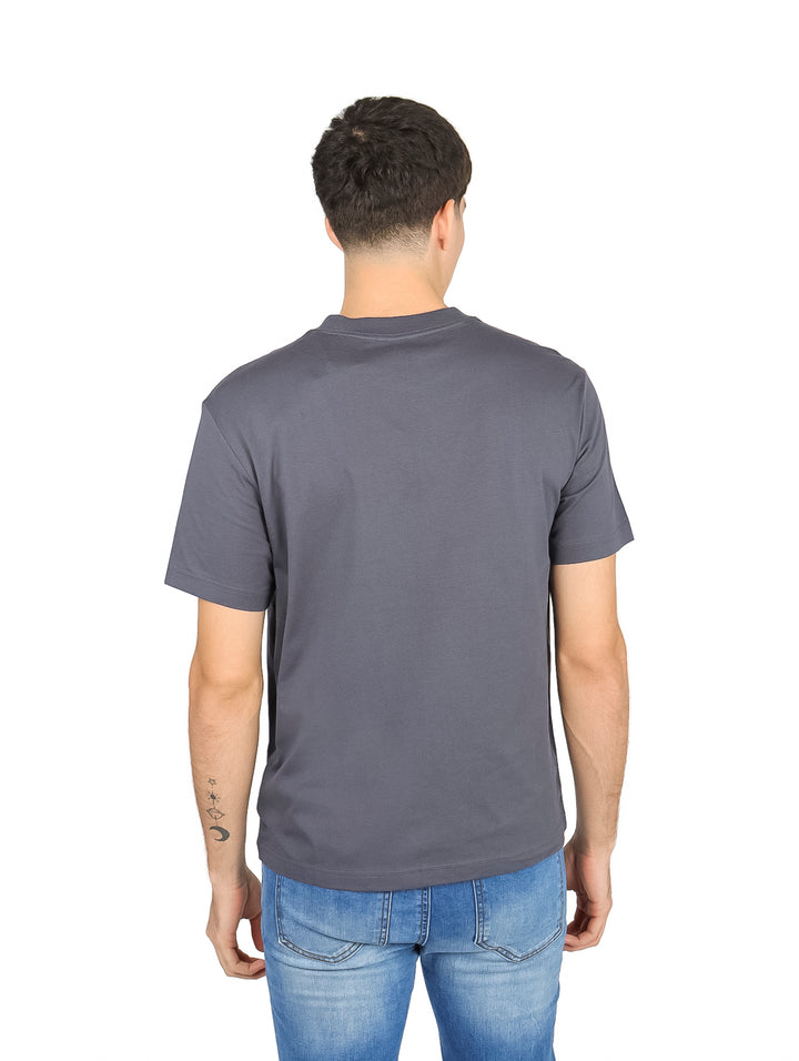Hombre vistiendo una camiseta de manga corta color gris oscuro con estampado de texto blanco en el pecho.