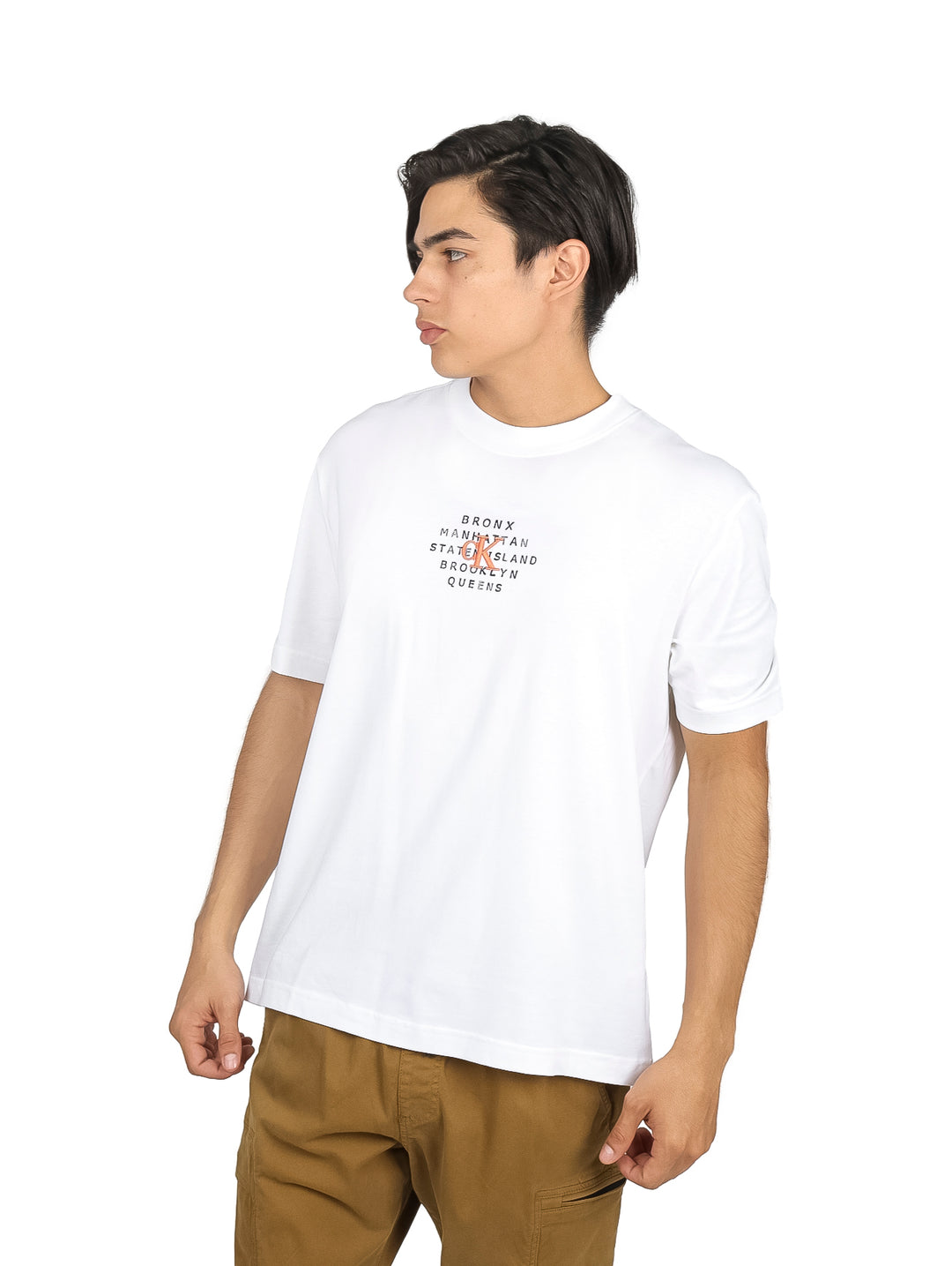 Hombre vistiendo playera blanca de manga corta Calvin Klein con texto en el pecho y pantalones caqui.