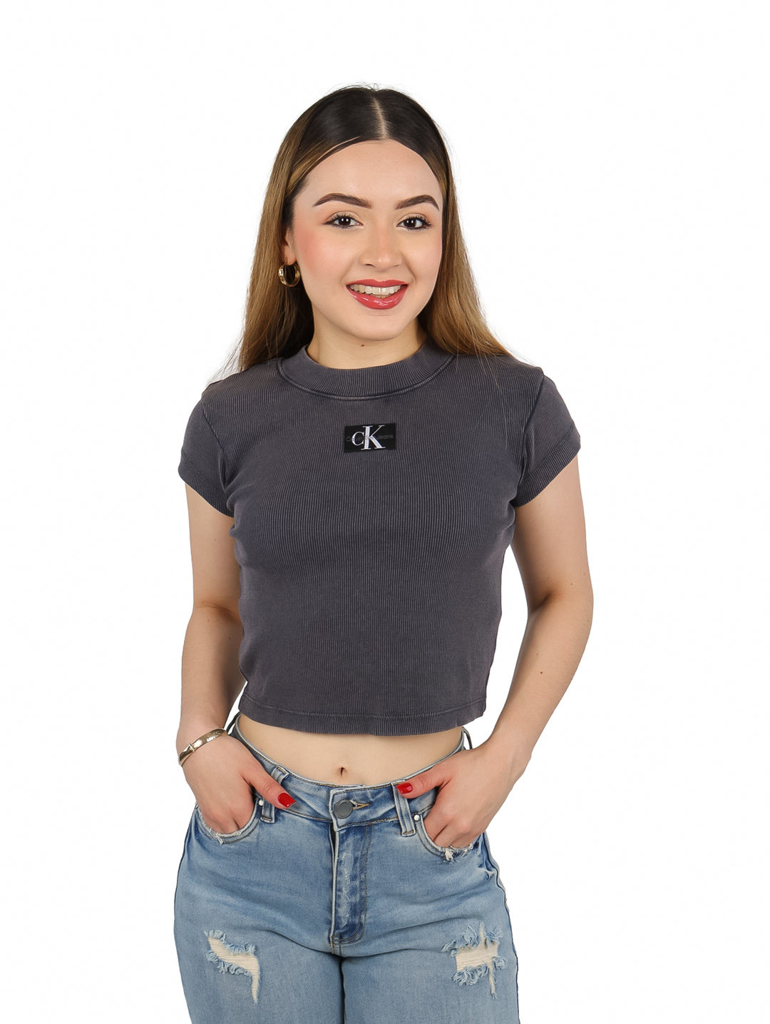 Mujer vistiendo una camiseta corta gris acanalada de Calvin Klein con logo en el pecho.