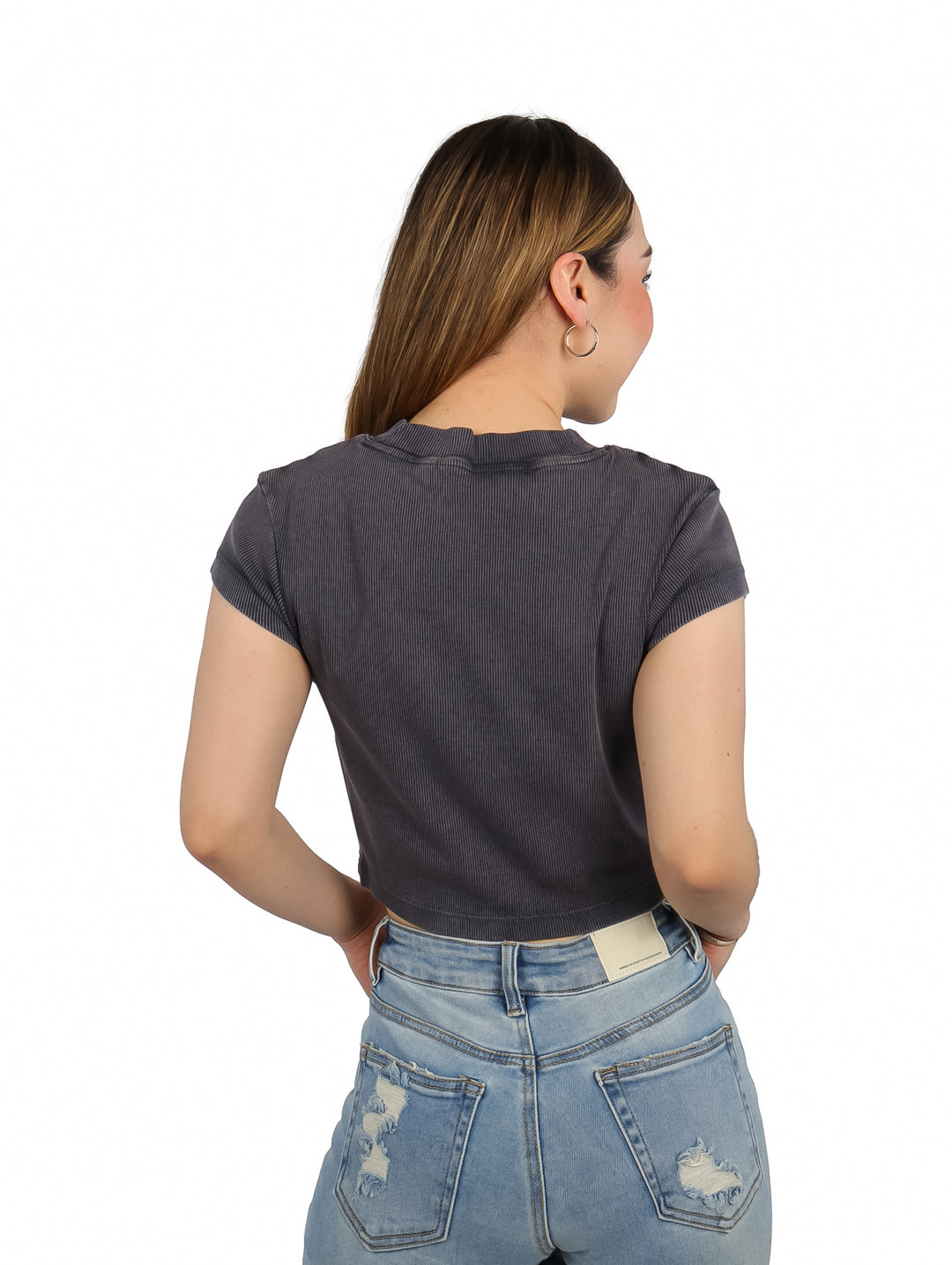 Mujer vistiendo una camiseta corta gris acanalada de Calvin Klein con logo en el pecho.