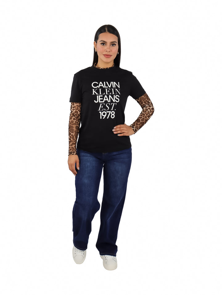 Mujer vistiendo playera negra de manga corta con estampado blanco de Calvin Klein Jeans.