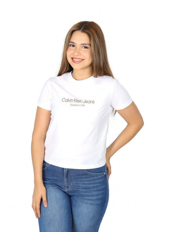 Mujer vistiendo una playera blanca de manga corta Calvin Klein y pantalones de mezclilla azules.