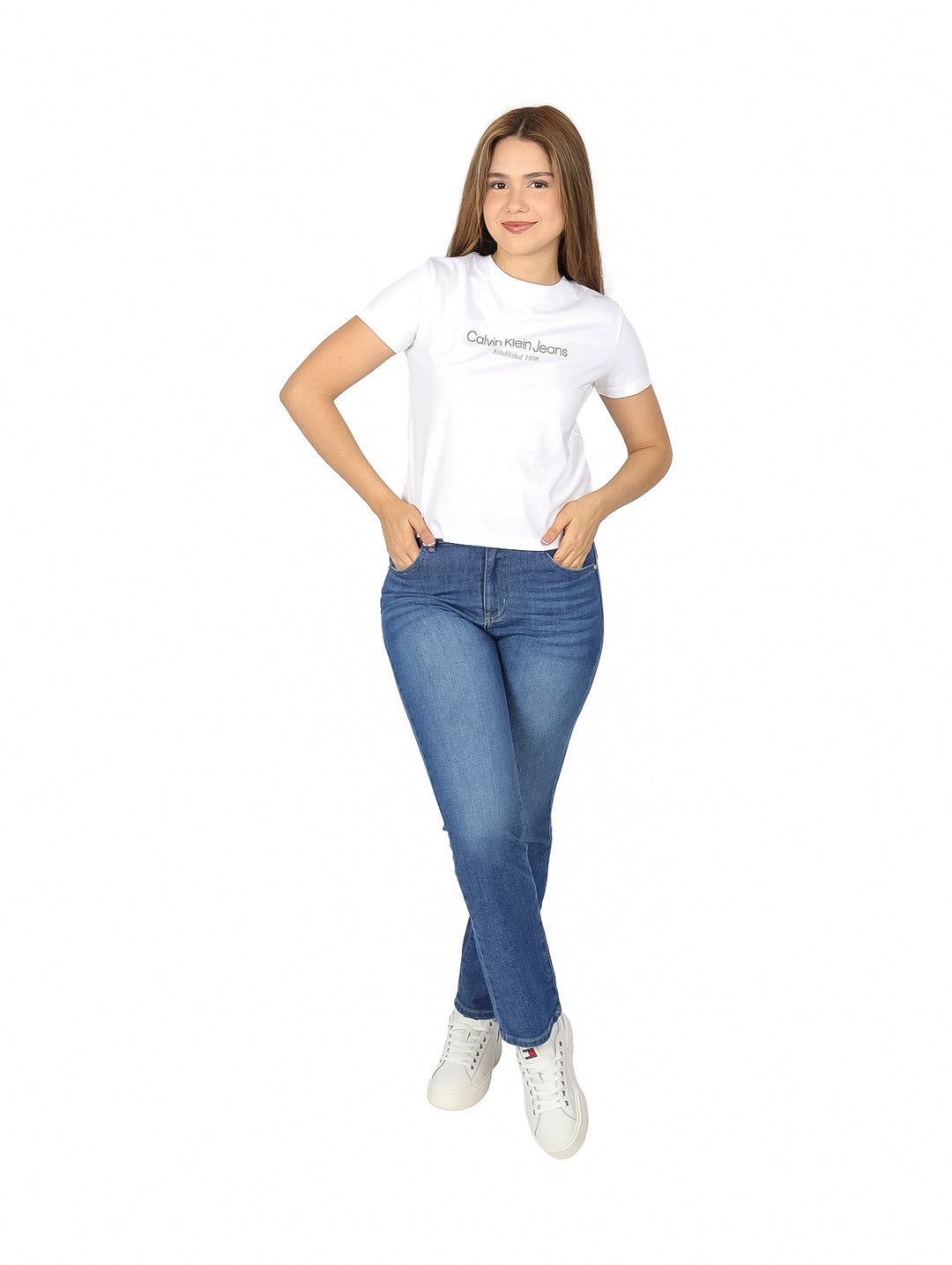 Mujer vistiendo una playera blanca de manga corta Calvin Klein y pantalones de mezclilla azules.
