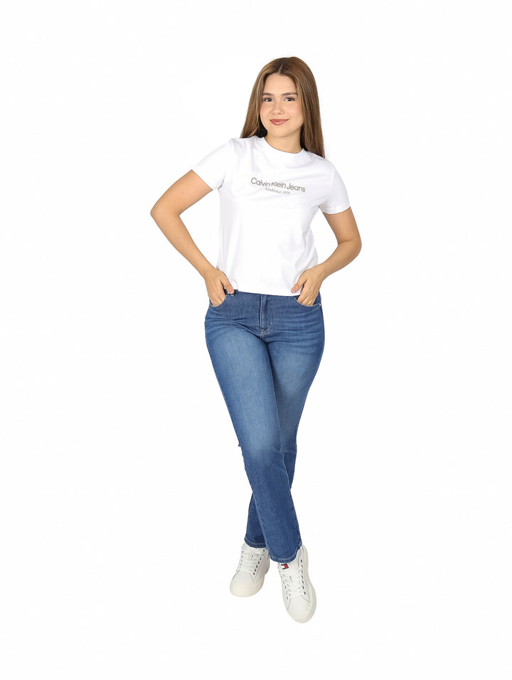 Mujer vistiendo una playera blanca de manga corta Calvin Klein y pantalones de mezclilla azules.