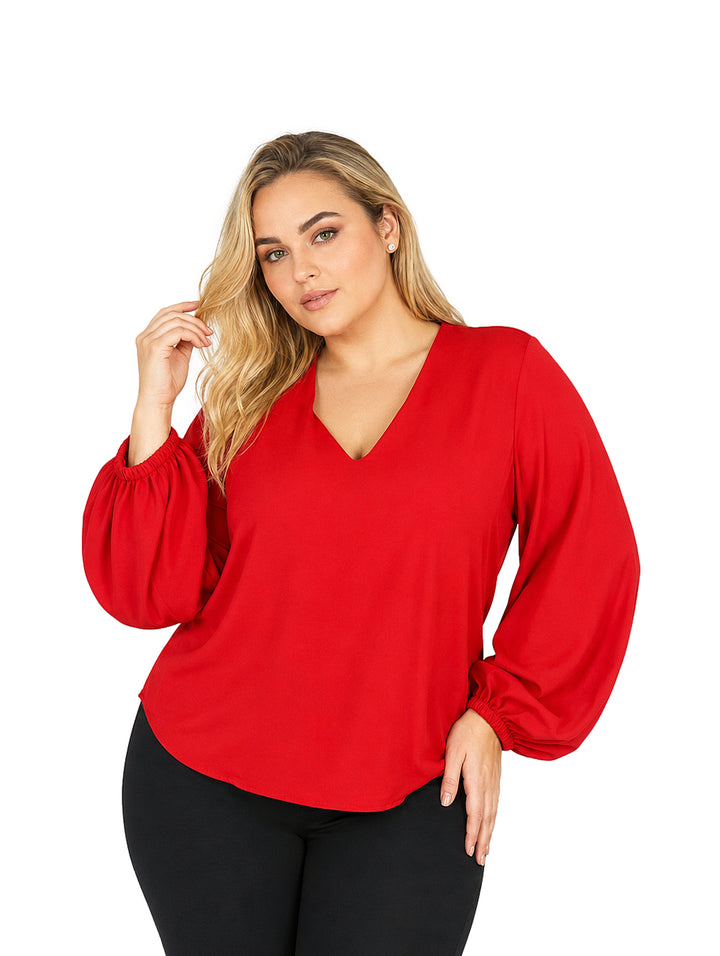 Mujer vistiendo una blusa roja de manga larga con cuello en V y mangas abullonadas.