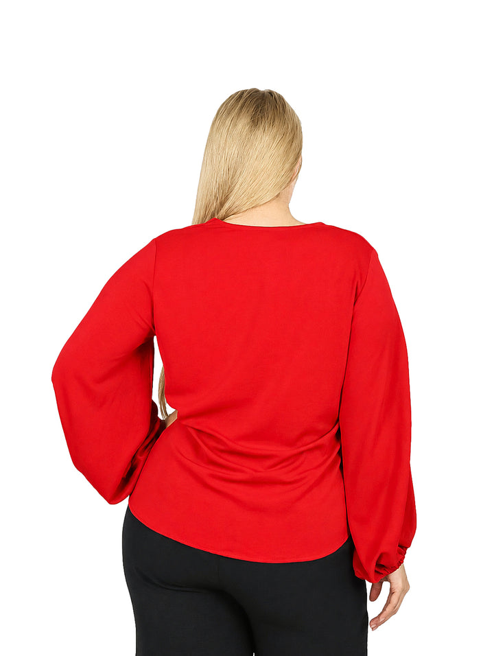 Mujer vistiendo una blusa roja de manga larga con cuello en V y mangas abullonadas.