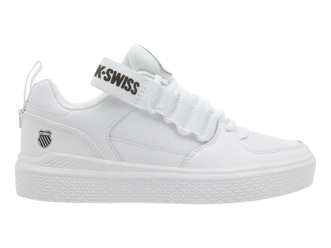 Tenis K-Swiss color blanco con agujetas y correa de velcro superior, suela blanca texturizada.