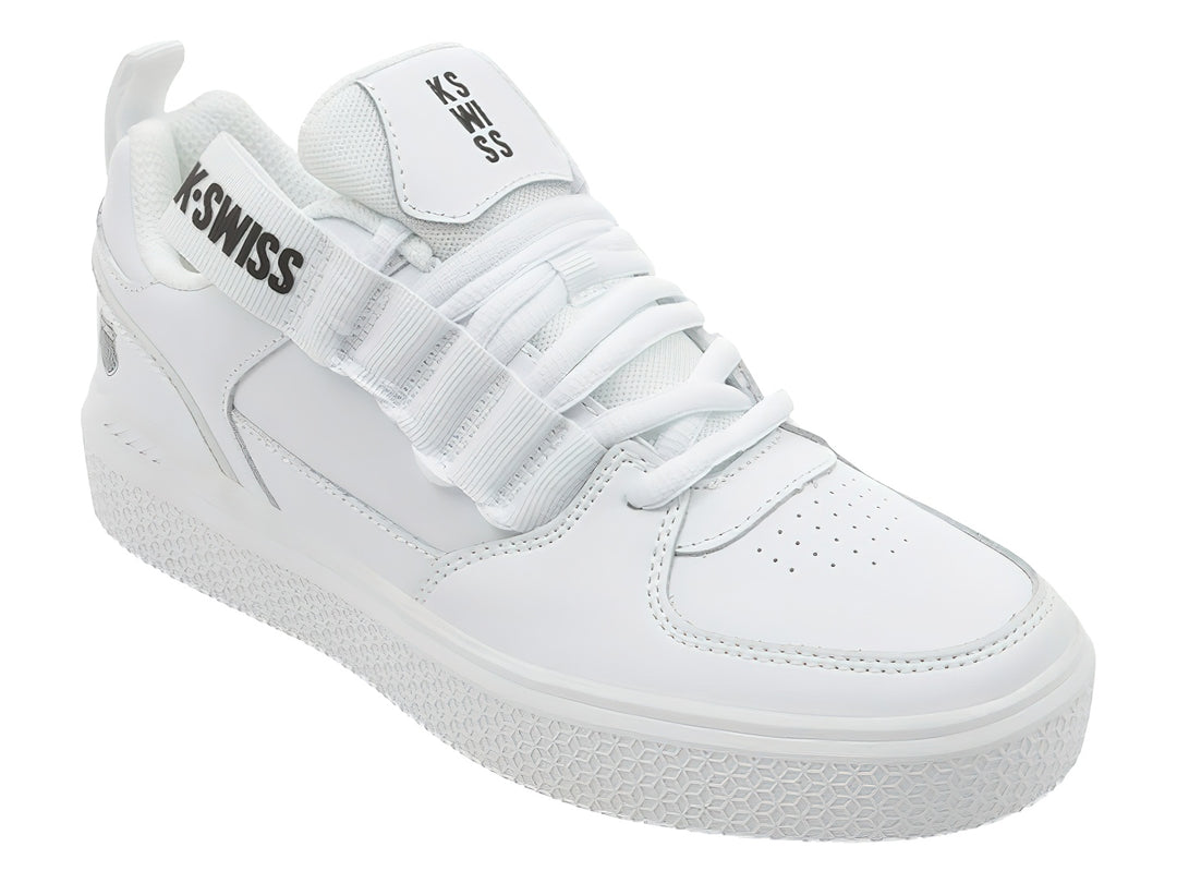 Tenis K-Swiss color blanco con agujetas y correa de velcro superior, suela blanca texturizada.