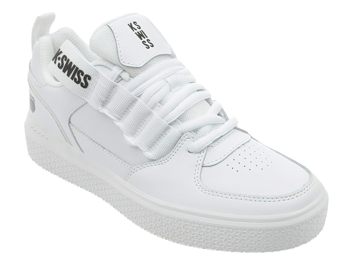 Tenis K-Swiss color blanco con agujetas y correa de velcro superior, suela blanca texturizada.