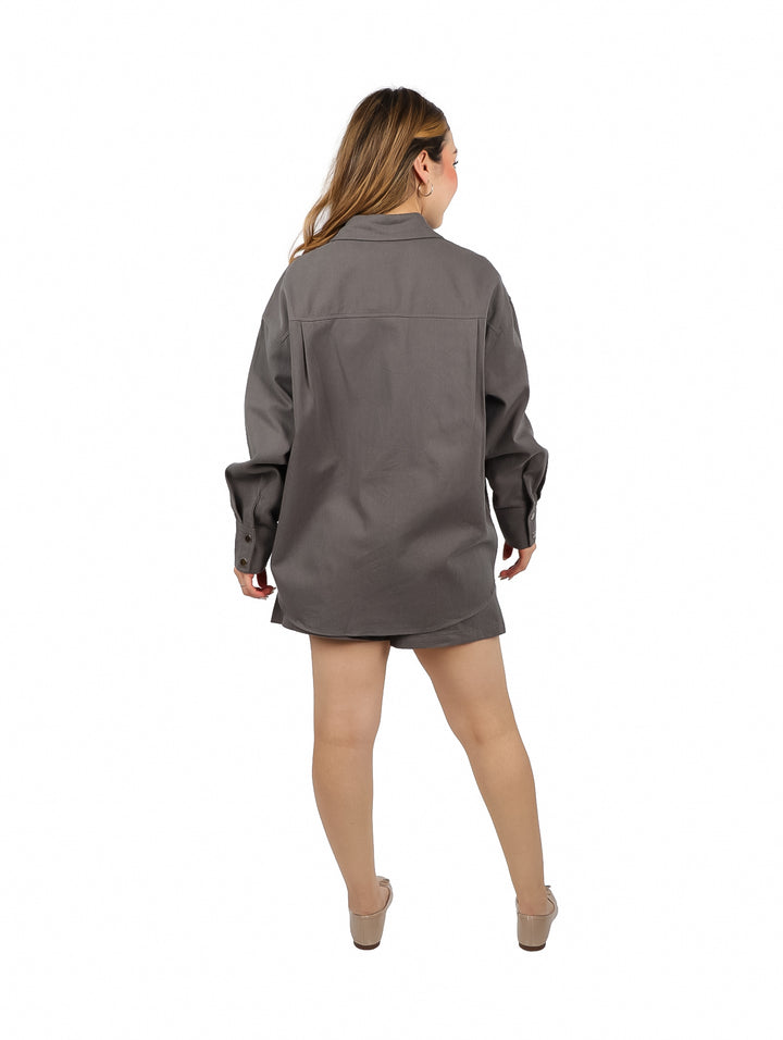 Mujer vistiendo un conjunto casual de color gris compuesto por una camisa de manga larga y un short.