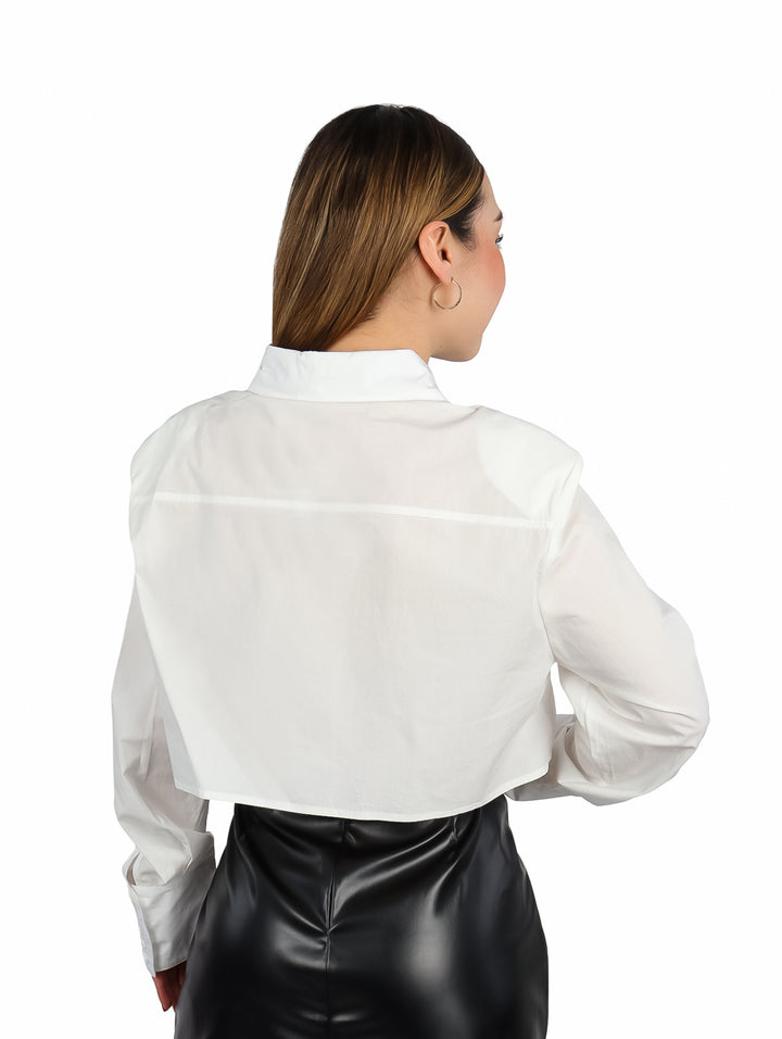 Mujer vistiendo camisa corta color ivory con detalle de cinturón negro y falda negra.