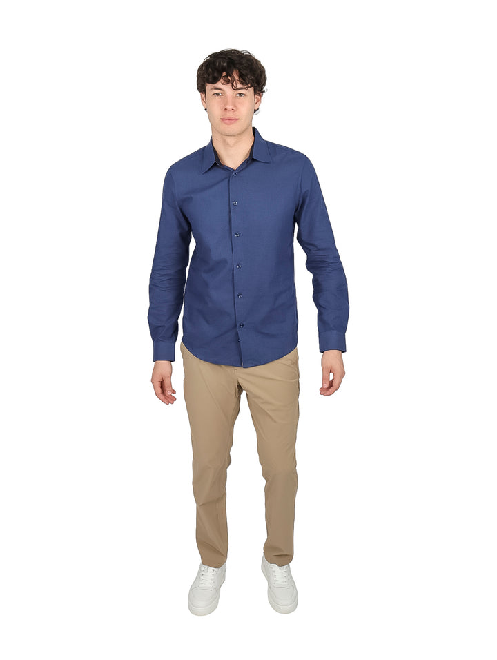 Hombre vistiendo una camisa de manga larga color azul marino y pantalones beige.