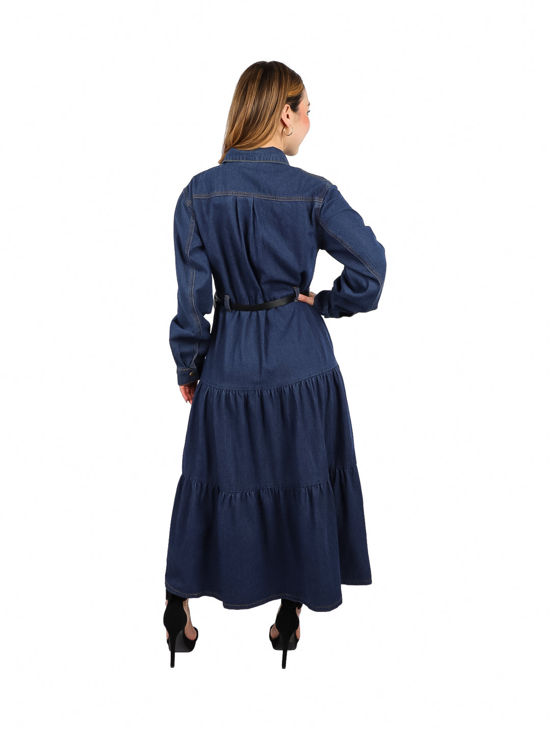 Mujer vistiendo un vestido largo de mezclilla azul oscuro con botones frontales, manga larga y cinturón negro.