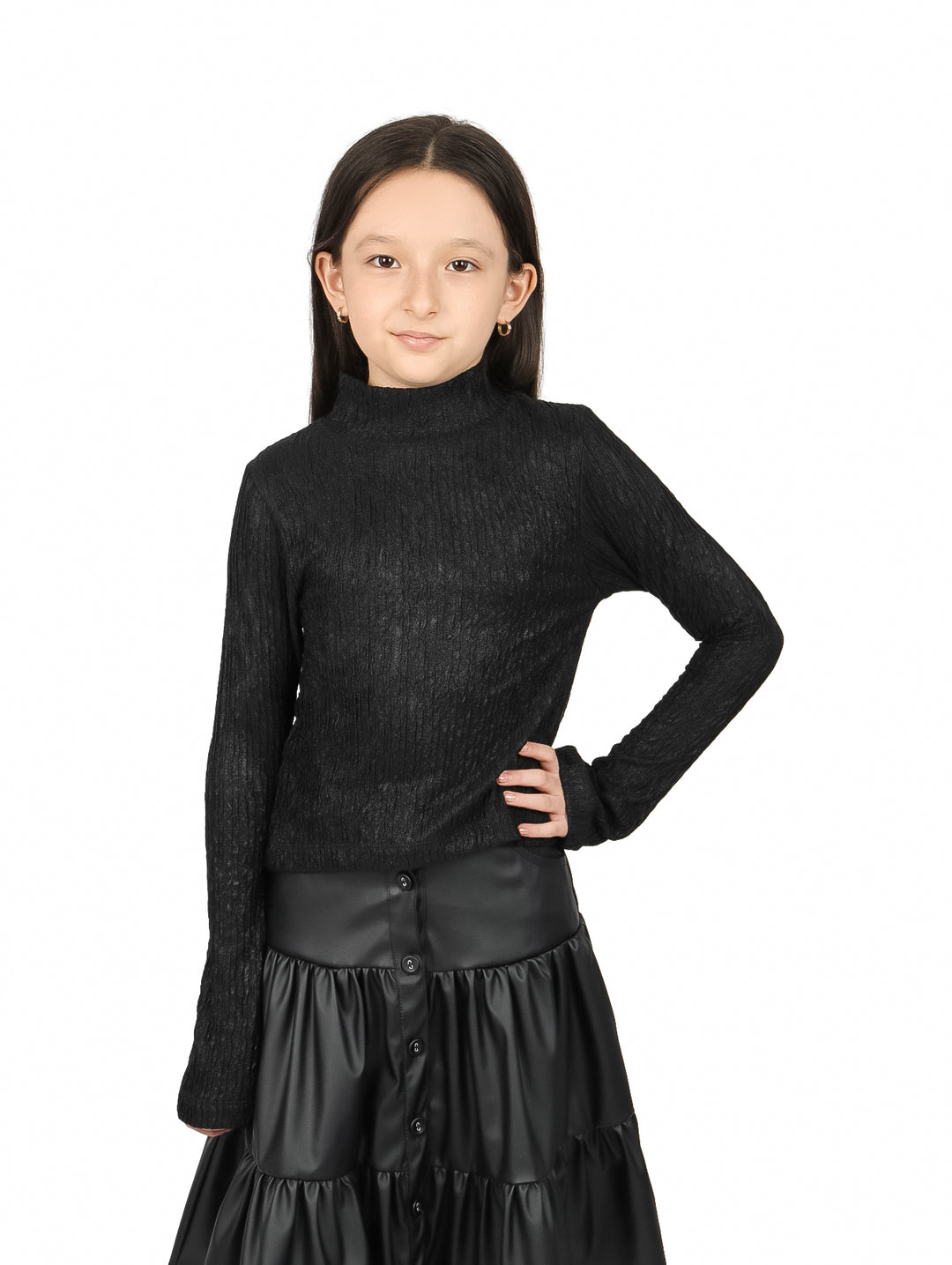 Niña vistiendo blusa negra de cuello alto y manga larga con falda de cuero negra.