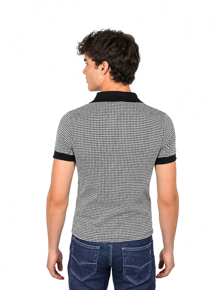 Hombre vistiendo camiseta tipo polo con estampado de cuadros pequeños en blanco y negro y cuello sólido negro.