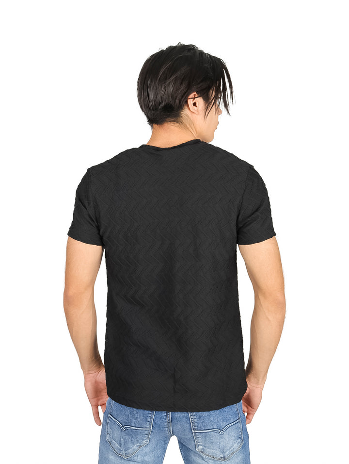 Hombre vistiendo playera negra de manga corta con textura geométrica sutil y cuello redondo.