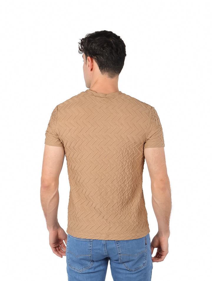 Hombre vistiendo playera de manga corta color marrón con textura geométrica en relieve y jeans azules.
