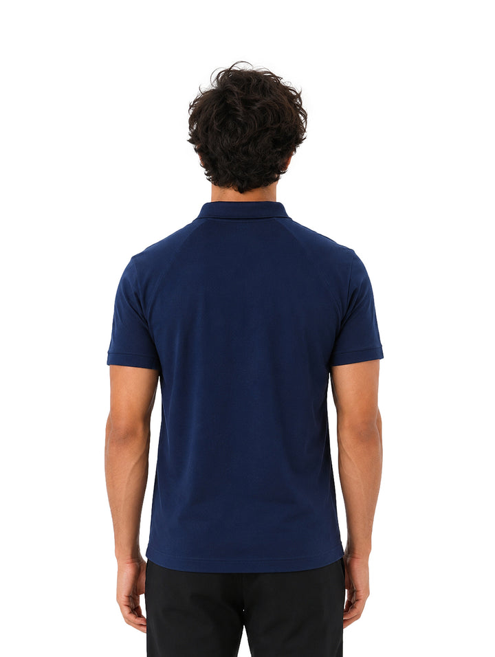 Hombre vistiendo playera polo Lacoste color azul marino de manga corta.