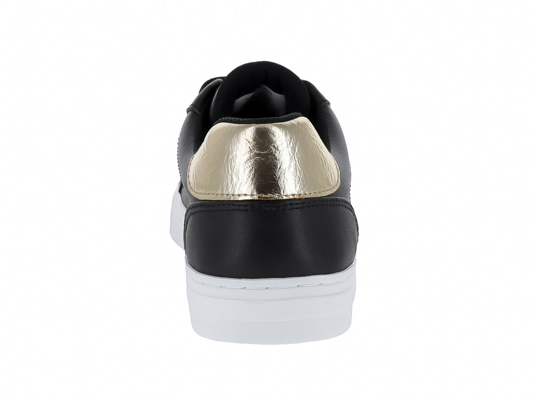 Tenis negros de cuero con detalle dorado en el talón y suela blanca.