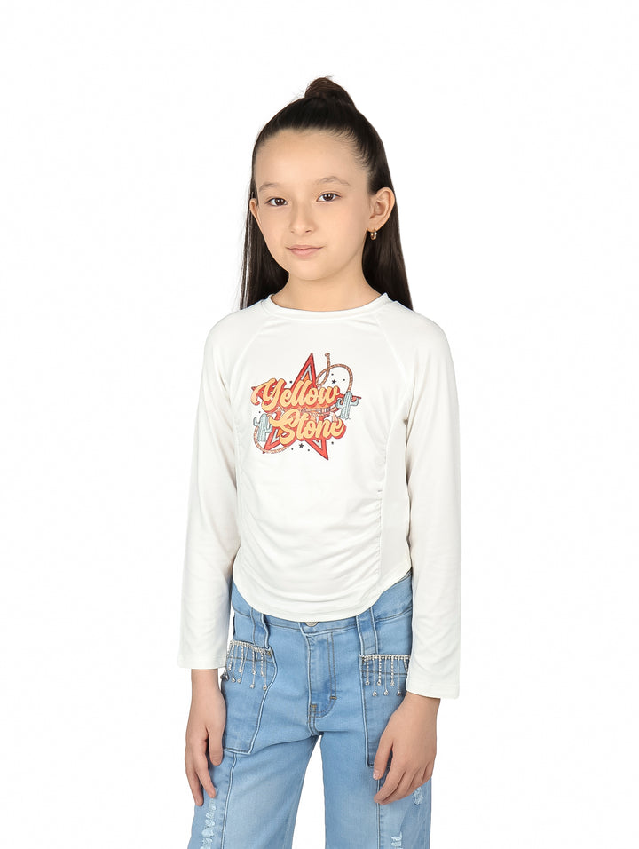 Niña vistiendo blusa color hueso de manga larga con estampado frontal y detalle corrugado lateral.
