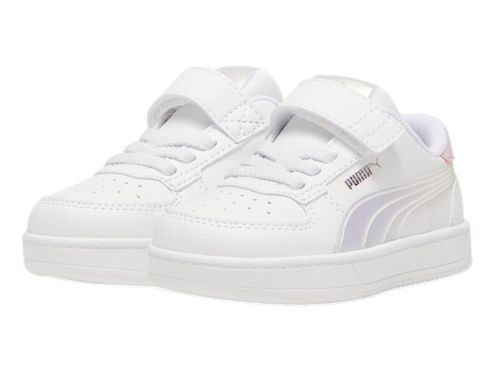Tenis PUMA blancos para niños con detalles en rosa y plateado holográfico, cierre de agujetas y correa de velcro.